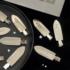 Silver metal seamless hair clips with engraved letters on a black decorative plate
