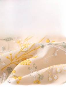 Close-up of floral embroidery on beige linen canvas makeup bag with detailed stitching