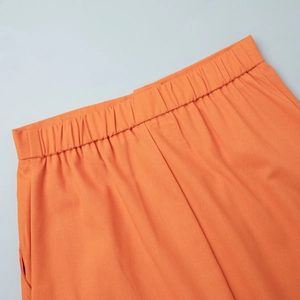 Detail of orange cotton linen pants showing elastic waistband and side pocket stitching