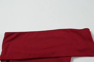 Detail of burgundy knitted one-shoulder dress showing tiered texture and premium fabric