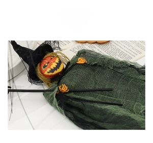 Detail view of Halloween pumpkin witch doll with orange skull hands and green mesh skirt