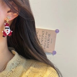 Detailed close-up of handmade beaded Santa Claus earrings with gold snowflake studs