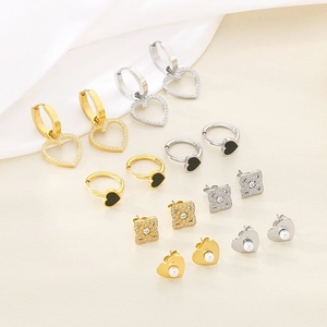 Détail de boucles d'oreilles cœur en strass et puces en perles en finitions or et argent