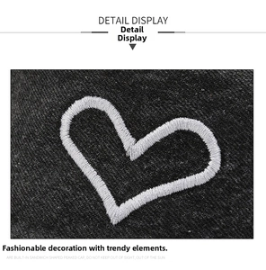 Detail of white heart embroidery on black washed denim fabric of a stylish bucket hat