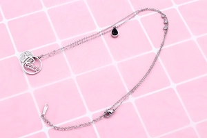 Close-up of double-layer silver steel necklace with Peace pendant and black teardrop stone