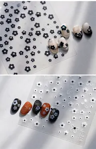 Detailed 3D nail art stickers featuring elegant black and white floral patterns with pearls
