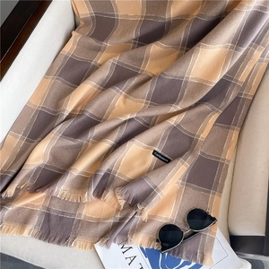 Detail of soft cashmere plaid scarf in brown and beige with elegant fringed edges