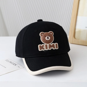 Détail d'une casquette bébé avec écusson ours et texte KIMI sur fond minimaliste
