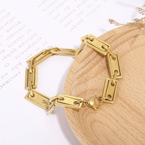 Macro shot of gold geometric rectangular chain bracelet with lobster clasp on wood