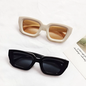 Fashionable thick frame cat eye sunglasses in cream and black on textured fabric