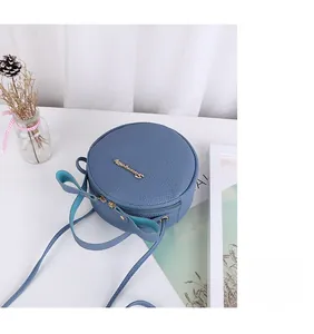 Macro detail of round lychee leather crossbody bag with bow and golden logo script