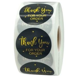 Detail showing a roll of round black Thank You stickers with gold foil heart lettering