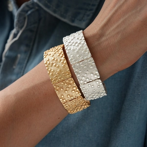 Détail de bracelets métalliques texturés dorés et argentés avec design rectangulaire