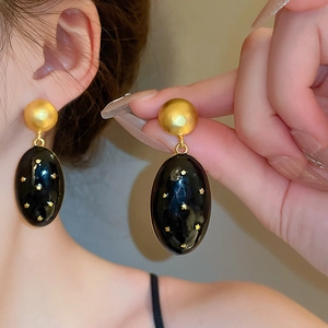 Close-up of vintage gold and black starry drop earrings on model showcasing elegant details