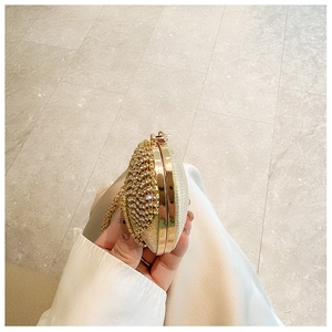 Close-up of golden oval evening clutch bag with sparkling rhinestones and metal frame