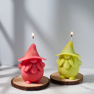 Detailed view of two lit gnome scented candles on rustic wood slices with marble background