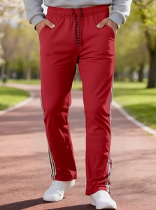 Detail of red joggers with black and white side stripes on a park running track