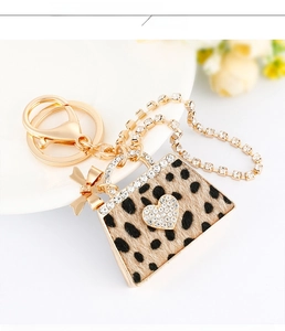 Close-up of leopard print handbag keychain with sparkling white rhinestones and golden bow
