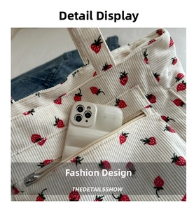 Close-up of strawberry print corduroy tote bag showing front zipper pocket with phone