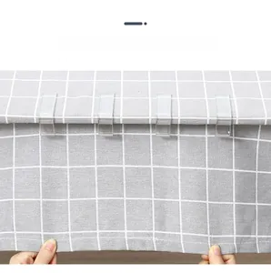 Close-up of four transparent U-shaped tablecloth clips fixing fabric on a checkered table
