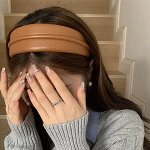 Gros plan d'un serre-tête large en cuir PU marron porté par un modèle en style vintage
