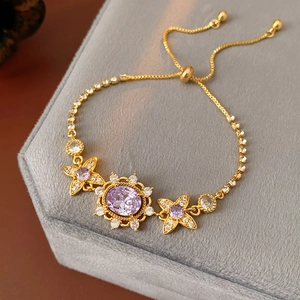 Detail of vintage gold bracelet with purple zircon flower and adjustable toggle chain
