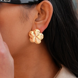 Close-up of golden five-petal flower stud earring featuring a polished metallic mirror finish
