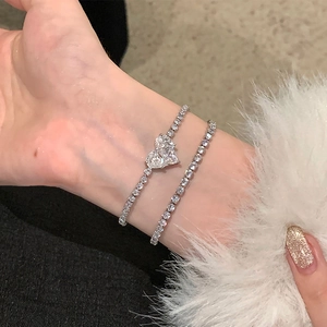 Gros plan d'un bracelet double couche en argent avec zircon coeur et chaîne tennis au poignet