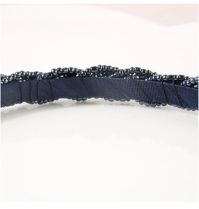 Macro shot of dark blue beaded headband with woven seed beads on a silk ribbon
