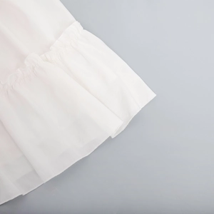 Detailed macro view of white chiffon dress hem featuring layered ruffle design