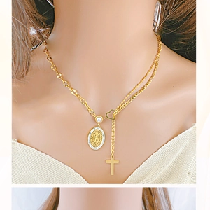 Detailed close-up of double-layered gold necklace with oval medallion and cross pendant