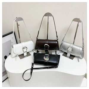 Row of four glossy baguette shoulder bags in white, brown, silver, and black on a white stand