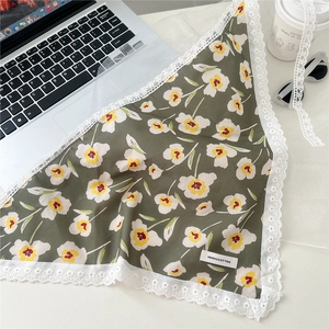 Detail of floral green triangle scarf with lace edges and a 100% cotton material label