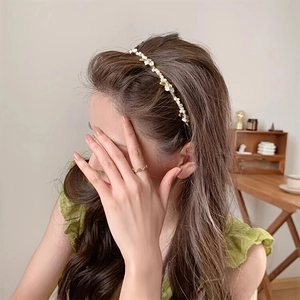 Elegant gold metal headband with white pearls and floral accents worn by a model