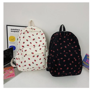 Corduroy backpacks in black and white with red strawberry patterns in a lifestyle setting
