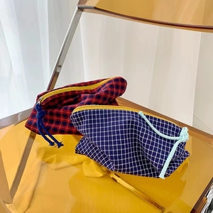 Detail of plaid makeup bags with vibrant yellow zippers and woven pulls on a yellow chair