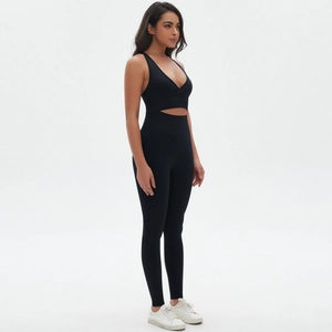 Detail of black cross-neck sports bra and high-waisted yoga leggings on model