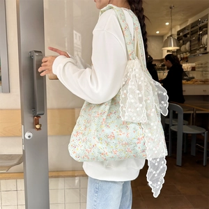 Detail of floral canvas tote bag featuring delicate white lace bow and hollow-out design