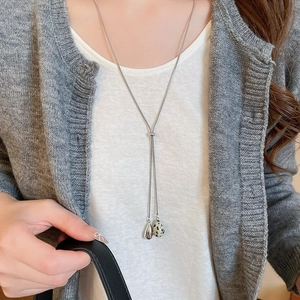 Close-up of a silver Y-shaped tassel necklace with spotted stone and metal teardrop charms