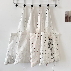 Detail view of canvas tote bags featuring heart prints in blue, pink, red, and black