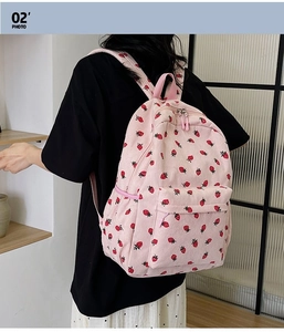 Detail of pink corduroy backpack featuring red strawberry patterns and front zipper pocket