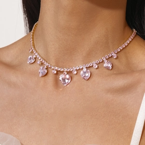 Macro shot of gold necklace with pink heart-shaped crystal and zirconia tassel detail