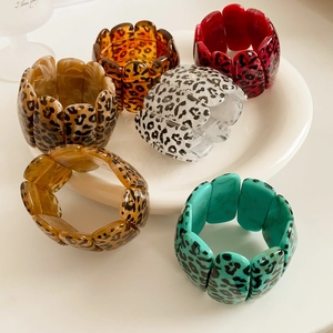 Détail de bracelets en acrylique imprimé léopard coloré dans un plateau en céramique