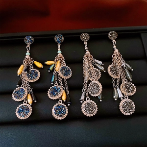 Détail de boucles d'oreilles ethniques à pompons avec strass et perles gouttes d'eau