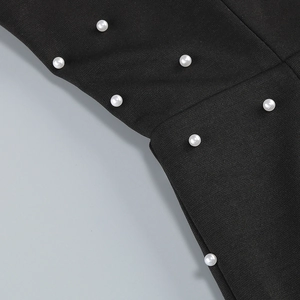 Détail des perles blanches brodées sur le tissu noir d'une robe à épaules dénudées