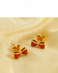 Détail de boucles d'oreilles nœud plaquées or 18 carats avec cristaux rouges sur soie