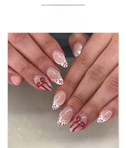 Detail of almond-shaped press-on nails with red 3D bows and lace floral patterns