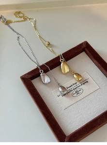 Detail of 18k gold and silver irregular pebble pendants on chains in a display tray