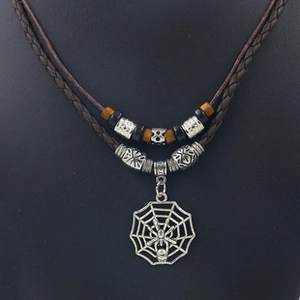 Macro-opname van de gevlochten leren ketting met spinnenweb hanger en metalen kralen