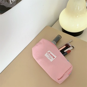 Detail view of pink macaron cosmetic bag with colorful zipper on a cozy desk setting